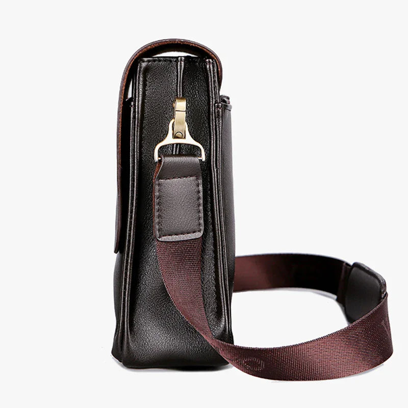 Black leather crossbody bag with a brown strap on a white background