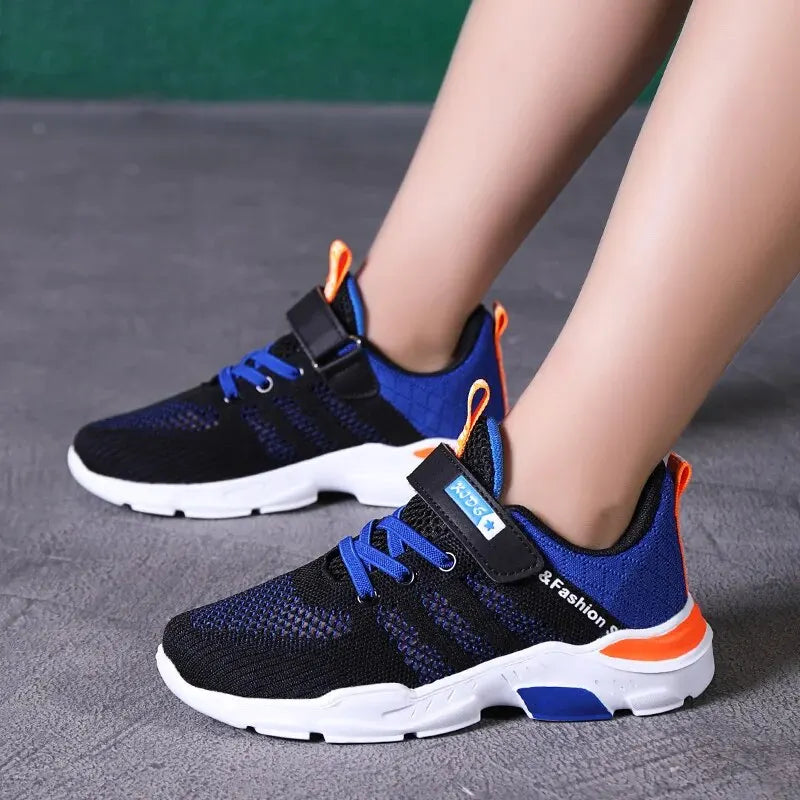Black and blue running shoes with orange accents worn by a person on a gray surface.